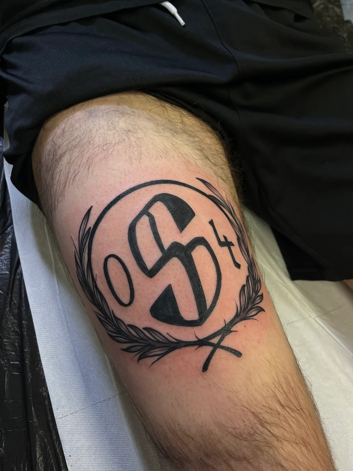 S04 Blackwork-Emblem mit Lorbeer am Bein von Tom